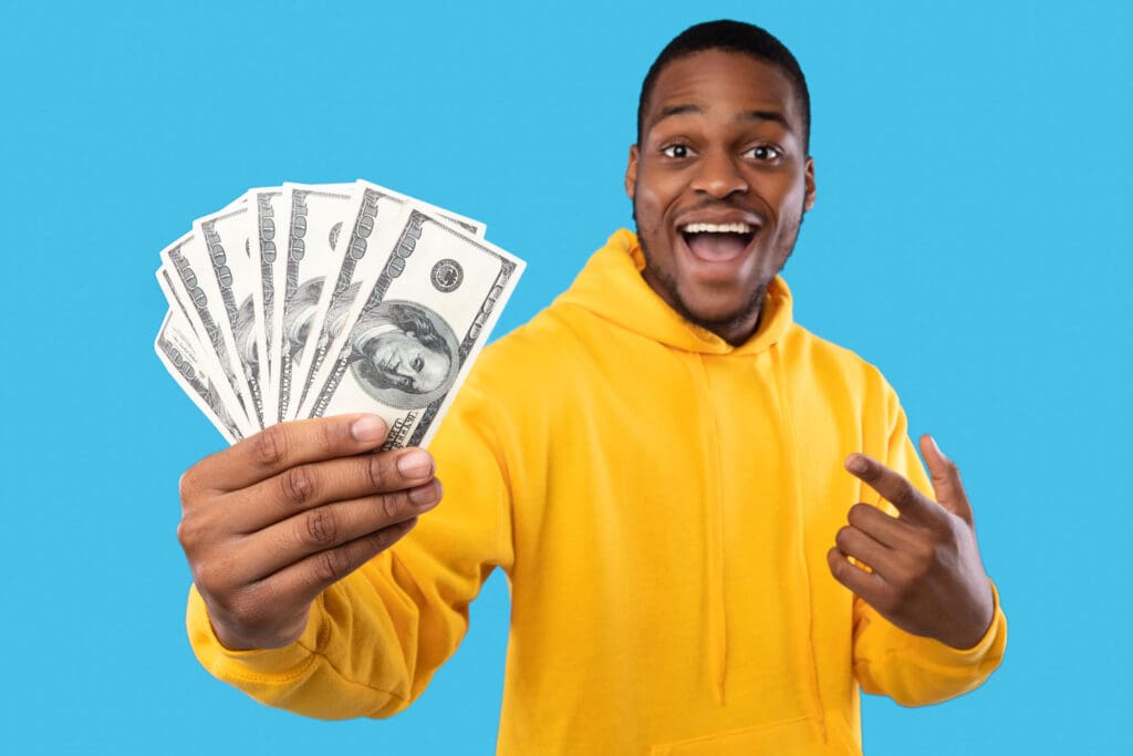 Man in a yellow shirt holding cash loan and smiling